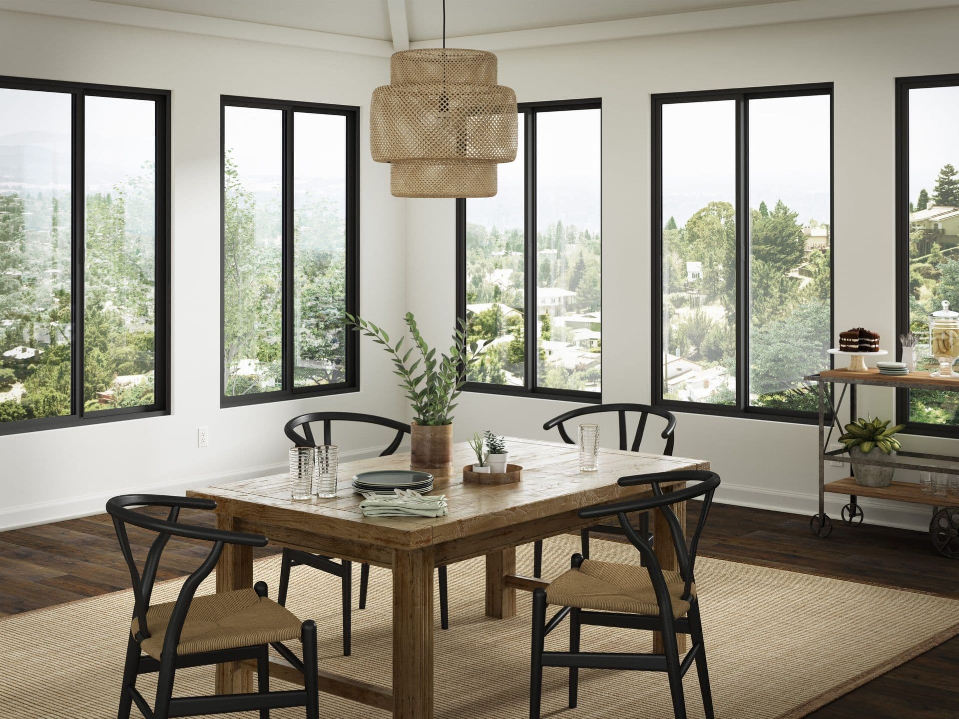 Modern dining room with wood table, black wishbone chairs, woven pendant light, and floor-to-ceiling windows overlooking forested hillside landscape